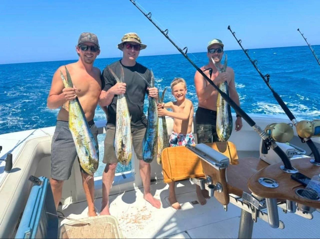 A family group, including a young angler, holds mahi aboard a High Z's boat